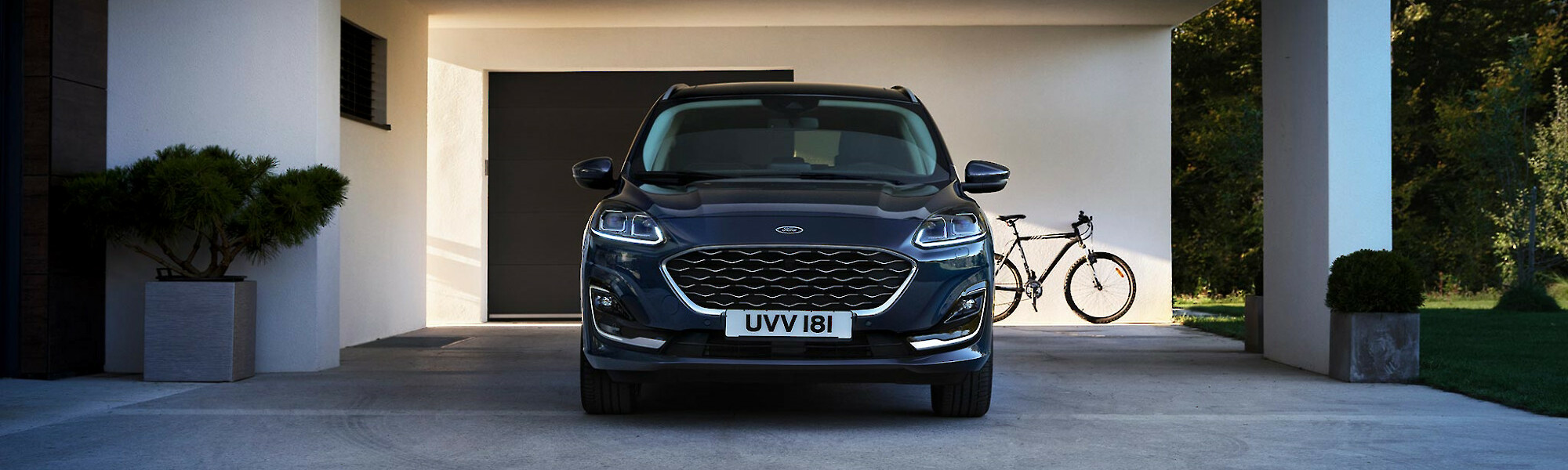 Ford Kuga PHEV áll egy modern családi ház beállója alatt