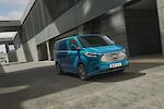 Kék Ford E-Transit Custom halad egy iparterületen